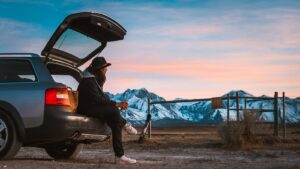 man sitting on car's tail looking at ranch